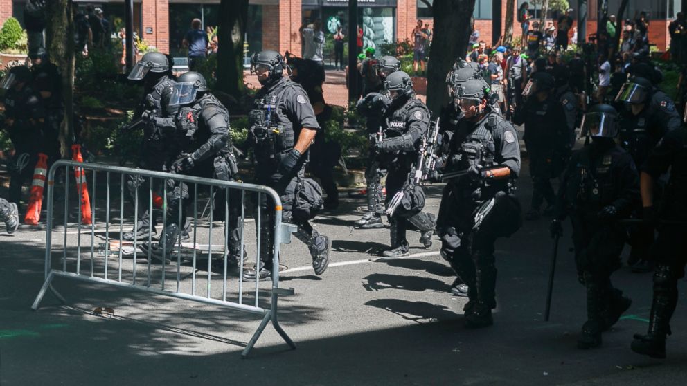Police move in on protesters during a rally in Portland, Ore., Saturday, Aug. 4, 2018. Small scuffles broke out Saturday as police in Portland, Oregon, deployed "flash bang" devices to disperse hundreds of right-wing and anti-fascist protesters.