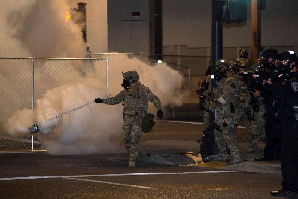 PHOTO: A federal law enforcement officer, deployed under the Trump administration's new executive order to protect federal monuments and buildings spreads tear gas during a protest over racial inequality in Portland, OR., July 17, 2020.