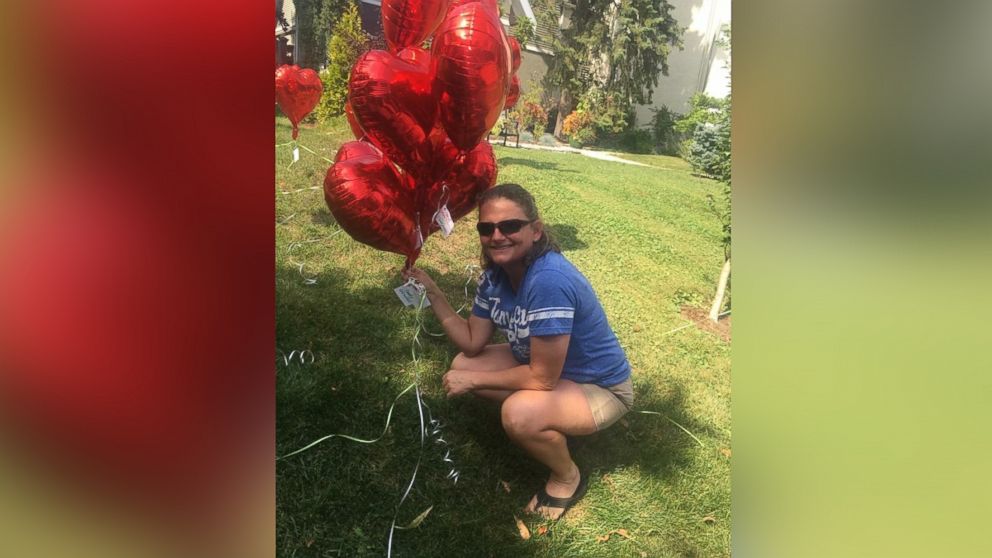 PHOTO: Michele Slack poses by one of the heart balloons she and neighbors of Laura Stegenga placed in Stegenga's front yard.