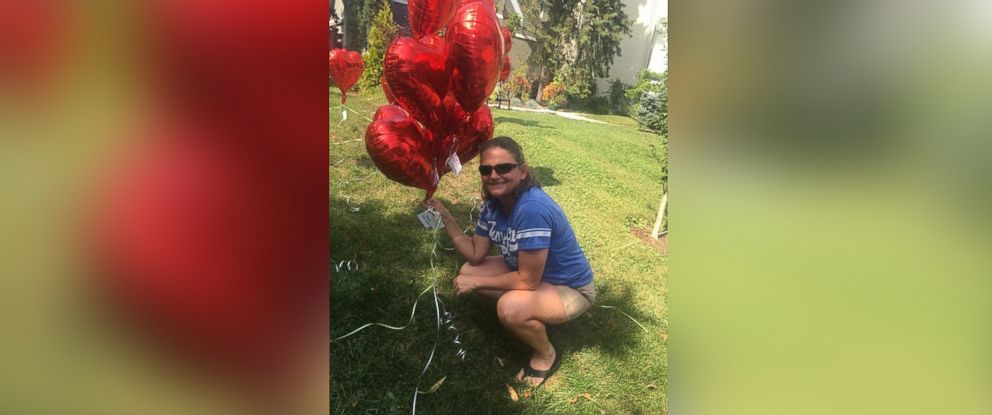 PHOTO: Michele Slack poses by one of the heart balloons she and neighbors of Laura Stegenga placed in Stegenga's front yard.
