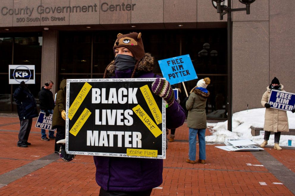 PHOTO: A demonstrator carries a Black Lives Matter sign in front of a group of demonstrators calling for Kim Potter's release on probation,Feb. 18, 2022 in Minneapolis.