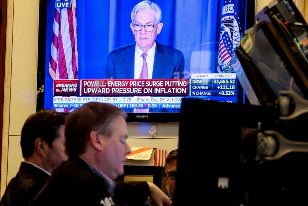 PHOTO: Traders work as Federal Reserve Chair Jerome Powell is seen delivering remarks on a screen at the New York Stock Exchange (NYSE) in New York City, March 16, 2022.
