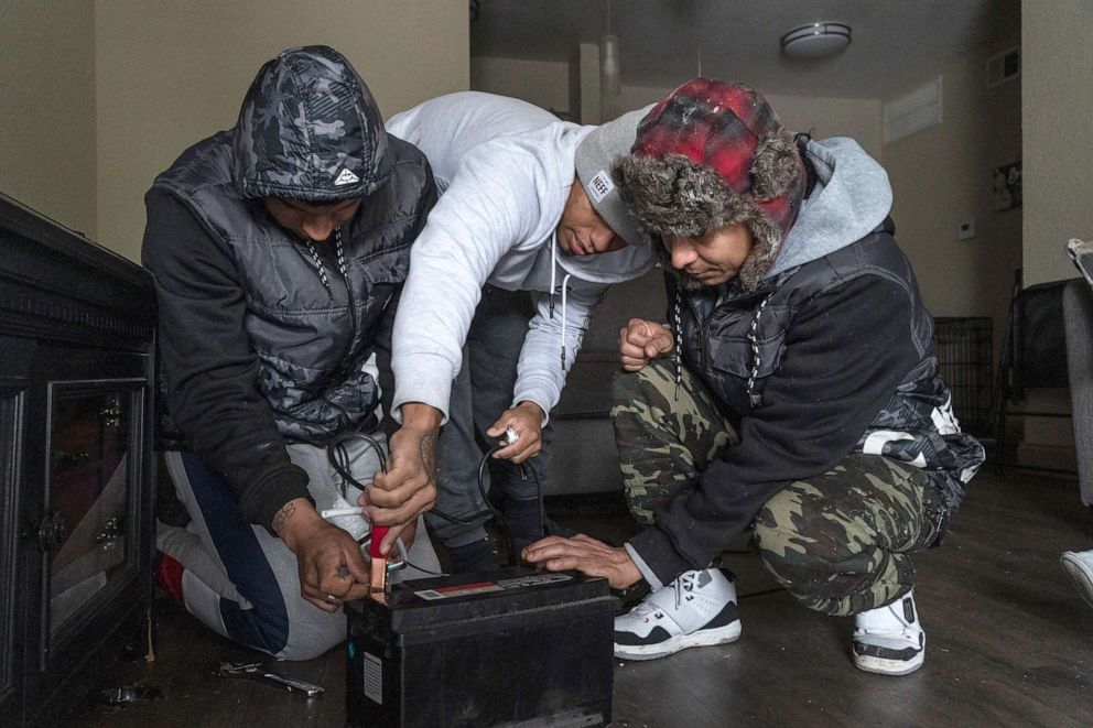 PHOTO: People try to connect power cables to a car battery to change their smartphones during a power outage on Feb. 16, 2021 in Houston. Winter storm Uri has brought historic cold weather, power outages and traffic accidents to Texas.