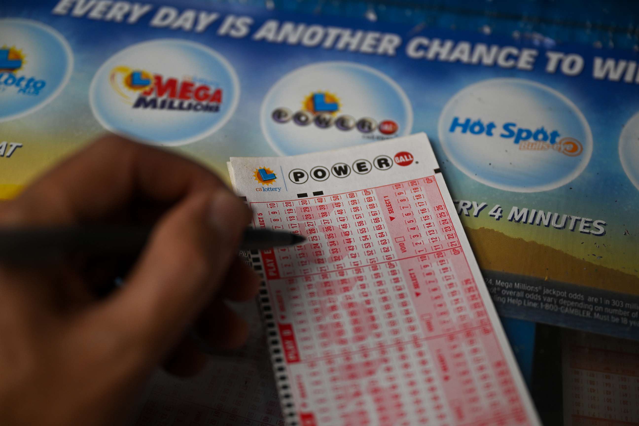 PHOTO: A person plays Powerball lottery at a gas station, July 11, 2023, in Trona, Calif.