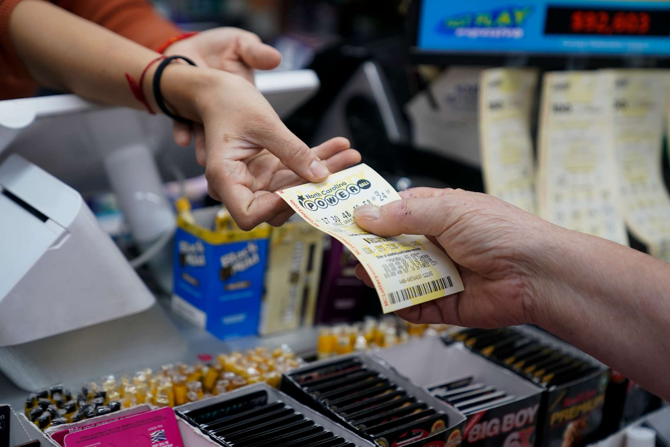 PHOTO: A store manager sells a Powerball ticket to a customer at Cigarettes and More in Pineville, North Carolina, on Oct. 4, 2023.
