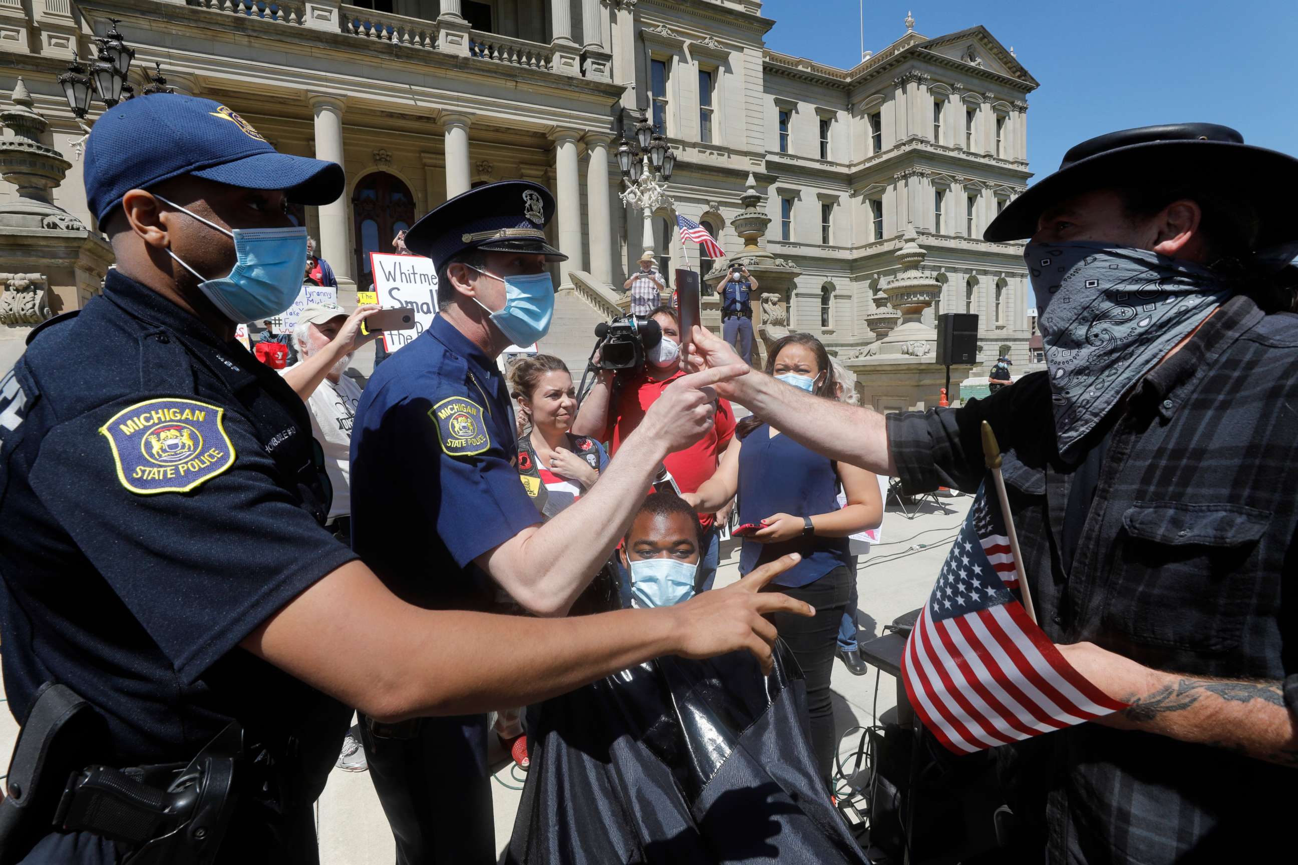 PHOTO: A person tries to help Angela Rigas as she gets a ticket for being a disorderly person as she cuts hair at the Michigan Conservative Coalition organized "Operation Haircut" outside the Michigan State Capitol in Lansing, Michigan on May 20, 2020.