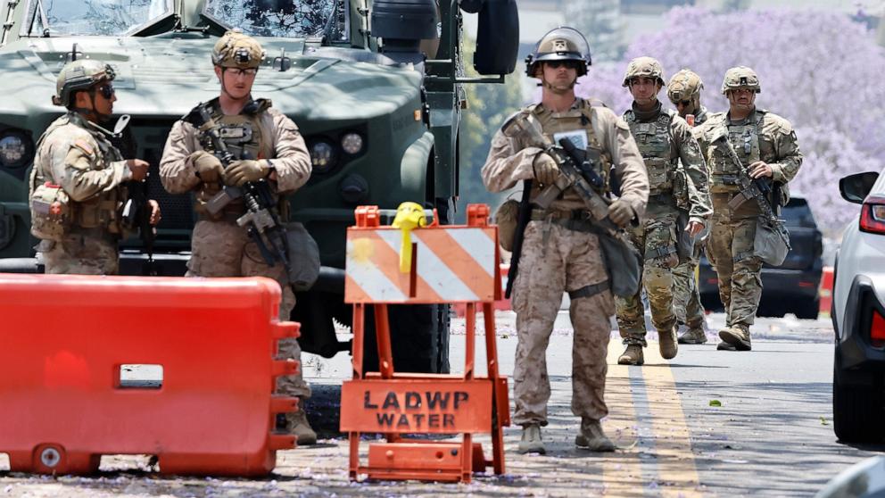 PHOTO: Marines and California National Guard soldiers guard an entrance to the Wilshire Federal Building, while standing by a Marines tactical vehicle, June 13, 2025, in Los Angeles.