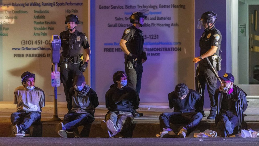 PHOTO: People sit in handcuffs under arrest during an emergency curfew during demonstrations following the death of George Floyd, May 31, 2020, in Santa Monica, California.