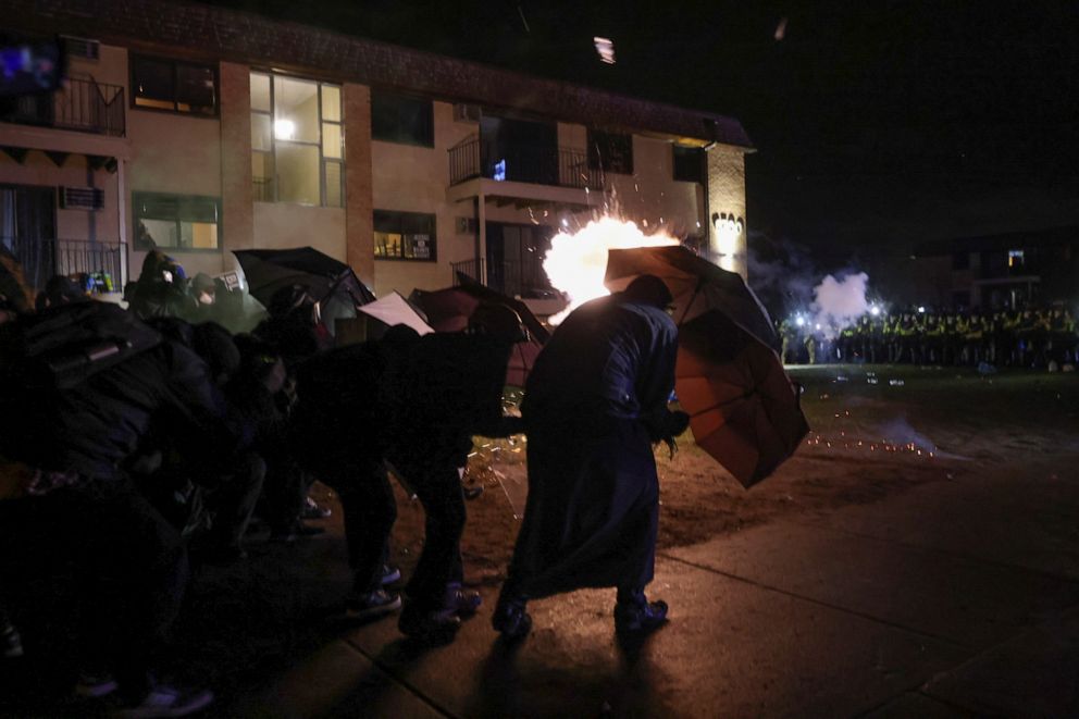 PHOTO: Protesters take cover behind umbrellas amid flash bangs set off by authorities while rallying near the Brooklyn Center Police Department in Brooklyn Center, Minnesota, on April 13, 2021, days after Daunte Wright was fatally shot by an officer.