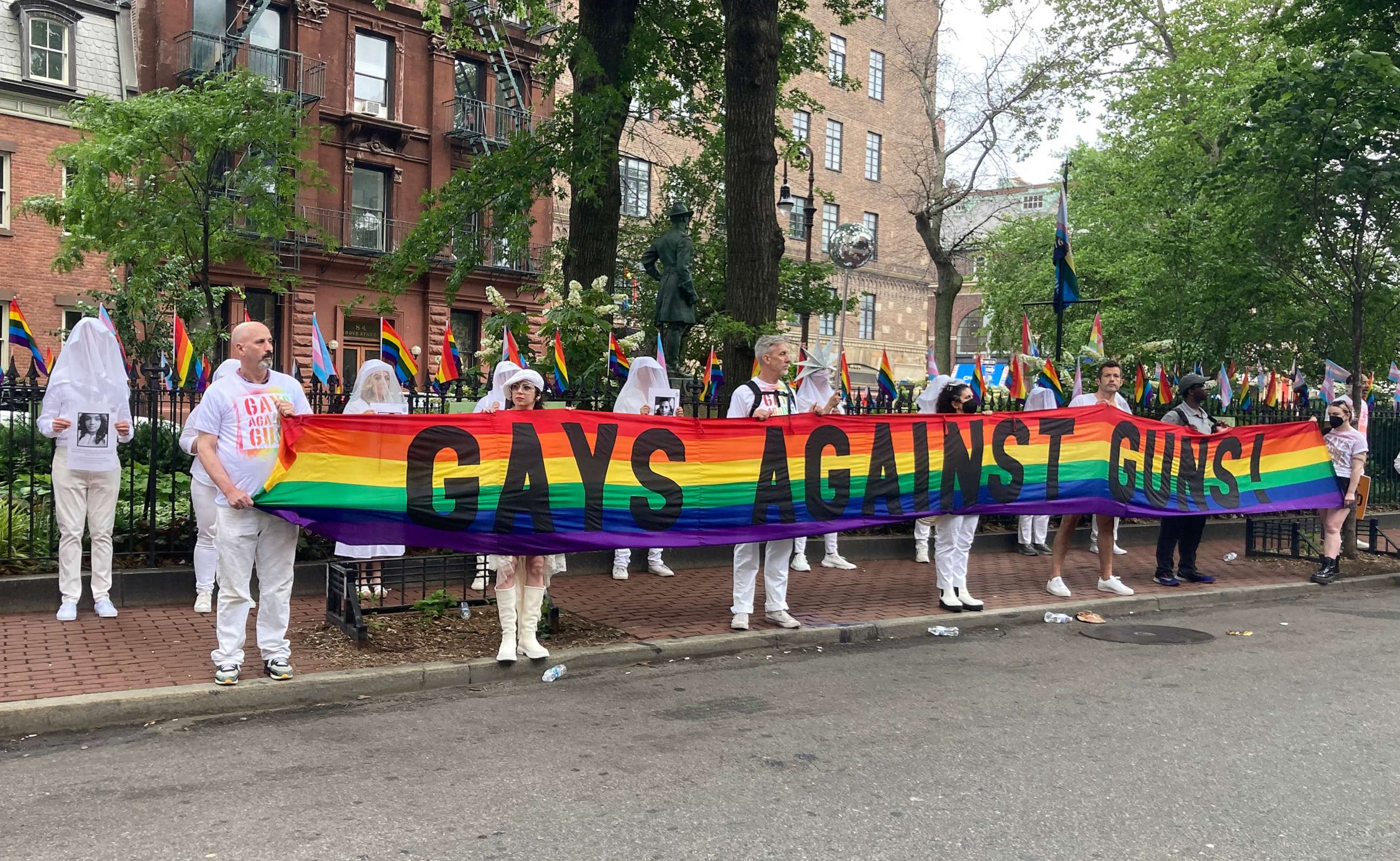 PHOTO: Across the street from the historic LGBTQ site, The Stonewall Inn, vigil participants hold a “Gays Against Guns” rainbow banner, June 12, 2023, in New York City.