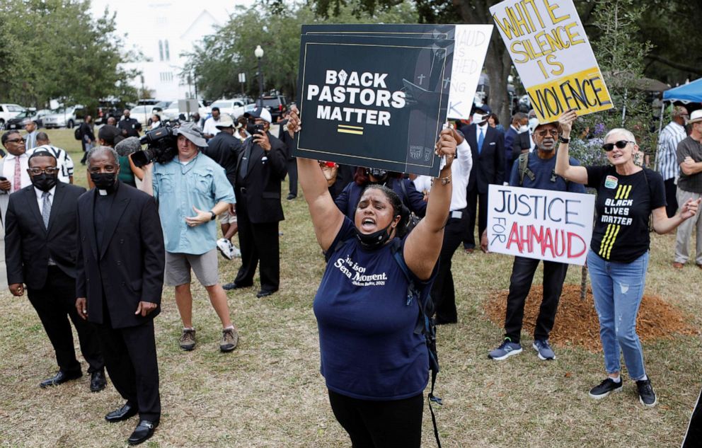 People hold signs as Reverend Al Sharpton and other pastors gather outside as Greg McMichael, his son Travis McMichael and William "Roddie" Bryan are tried in the Glynn County Courthouse for the killing of Ahmaud Arbery, in Brunswick, Ga., Nov. 18, 2021.