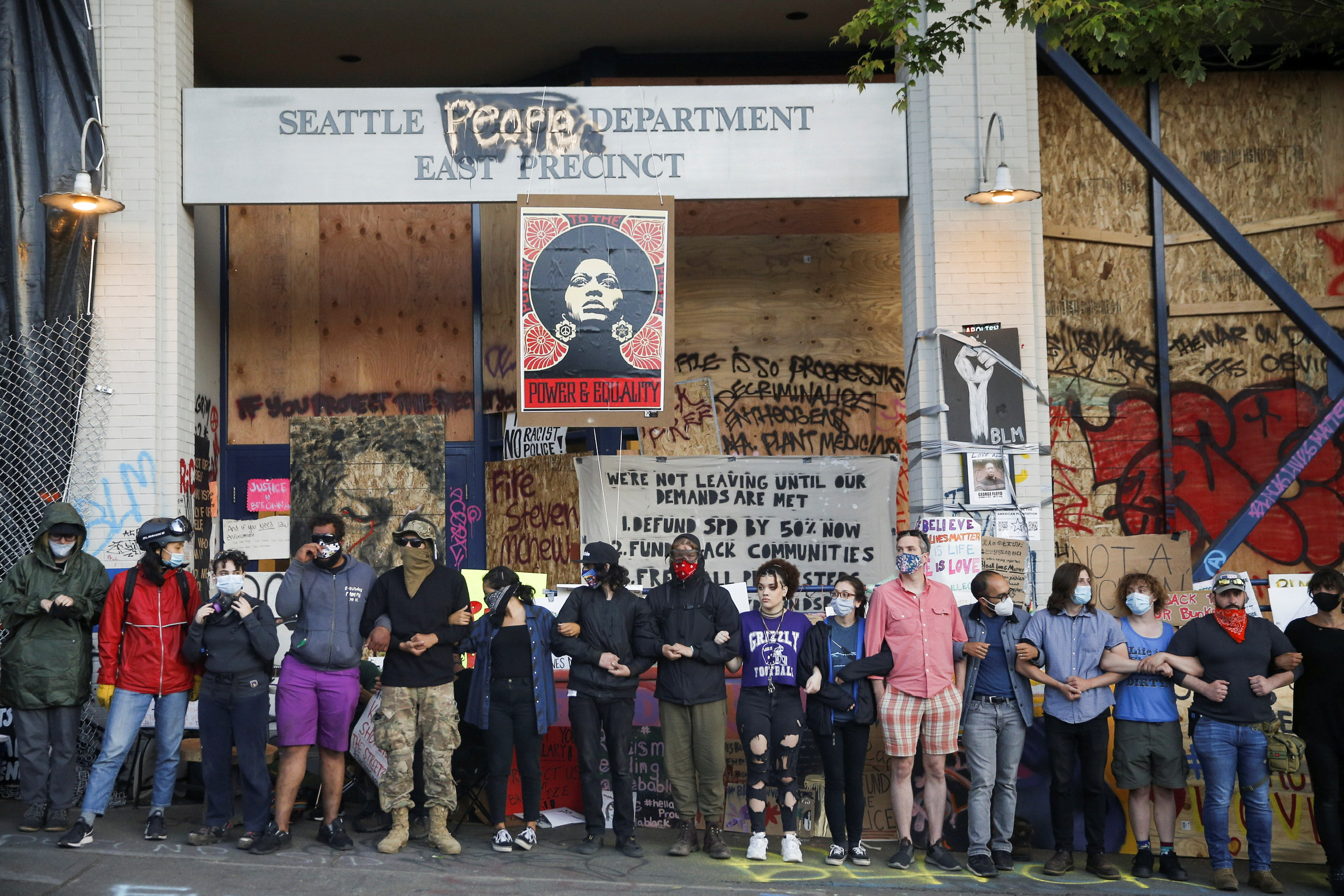 PHOTO: Protesters link arms in front of the Seattle Police Department's East Precinct within the boundaries of the so-called Capitol Hill Organized Protest zone, or CHOP, in Seattle, Washington, on June 22, 2020.