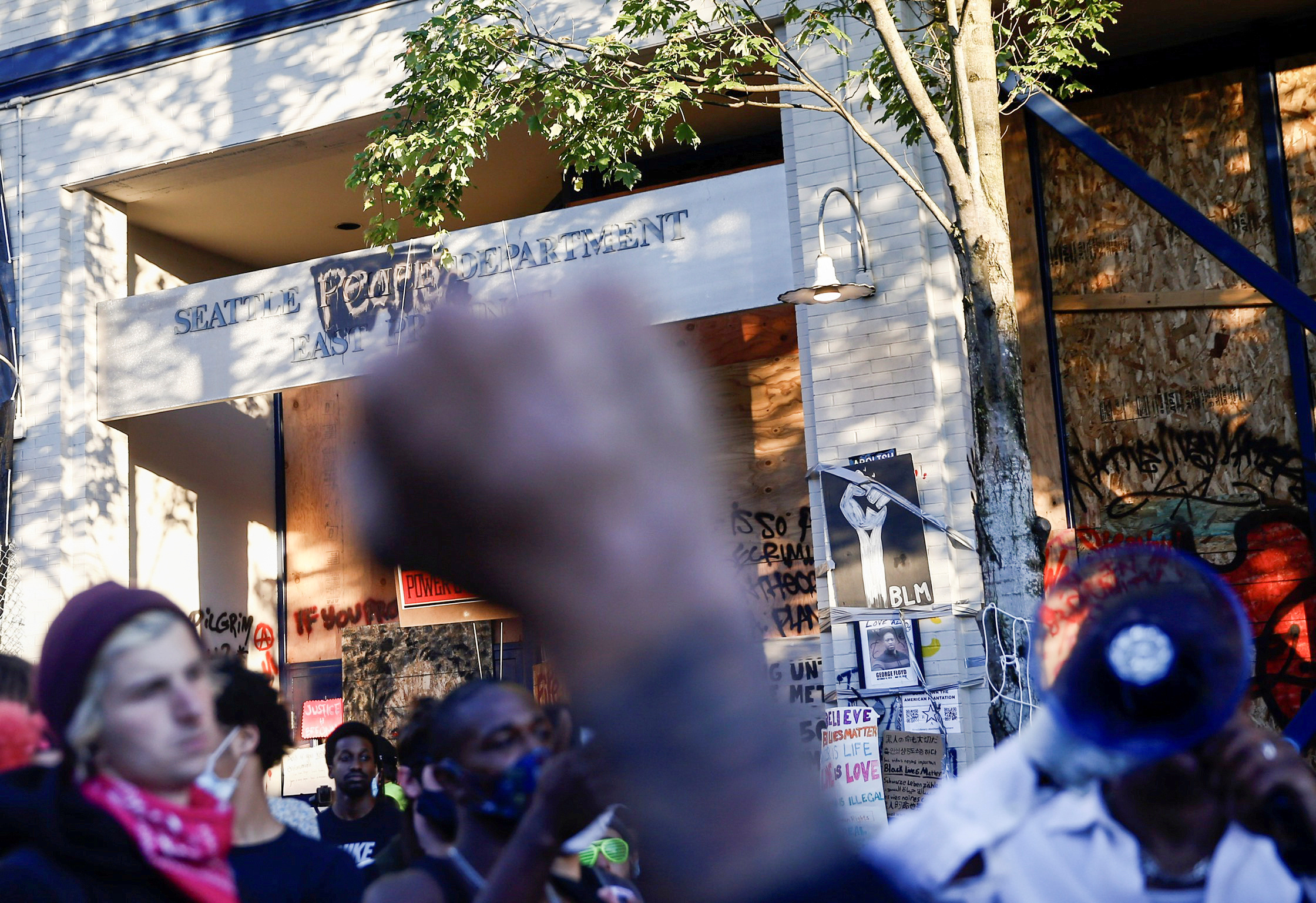 PHOTO: A protester raises a fist as others discuss strategies outside the Seattle Police Department's East Precinct within the boundaries of the so-called Capitol Hill Organized Protest zone, or CHOP, in Seattle, Washington, on June 22, 2020.