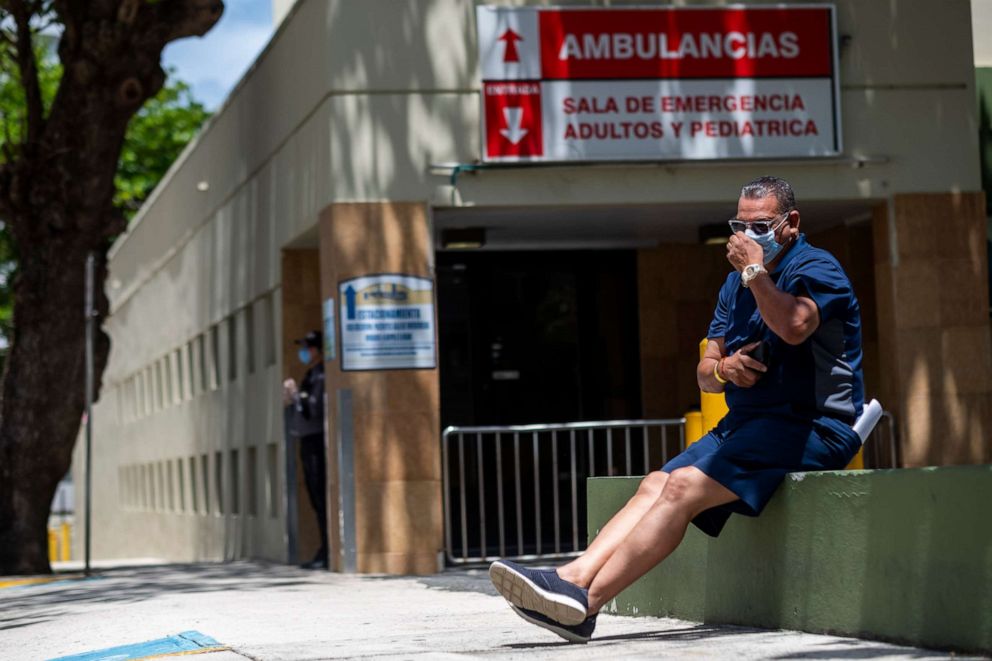 PHOTO: A man wearing a surgical mask sits in front of the emergency room entrance of the Ashford Presbyterian Community Hospital where the first coronavirus patient on the island died earlier in the day in San Juan, Puerto Rico, March 21, 2020.