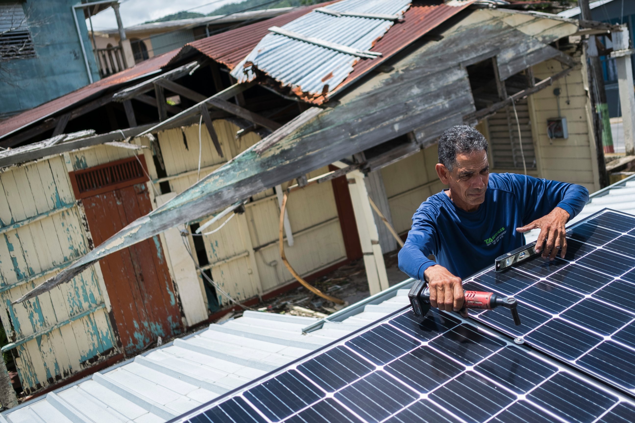 In this July 24, 2018 photo, Julio Rosario installs a solar energy system at a home in Adjuntas, Puerto Rico. 