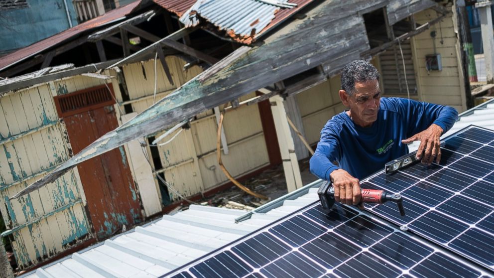 In this July 24, 2018 photo, Julio Rosario installs a solar energy system at a home in Adjuntas, Puerto Rico. 