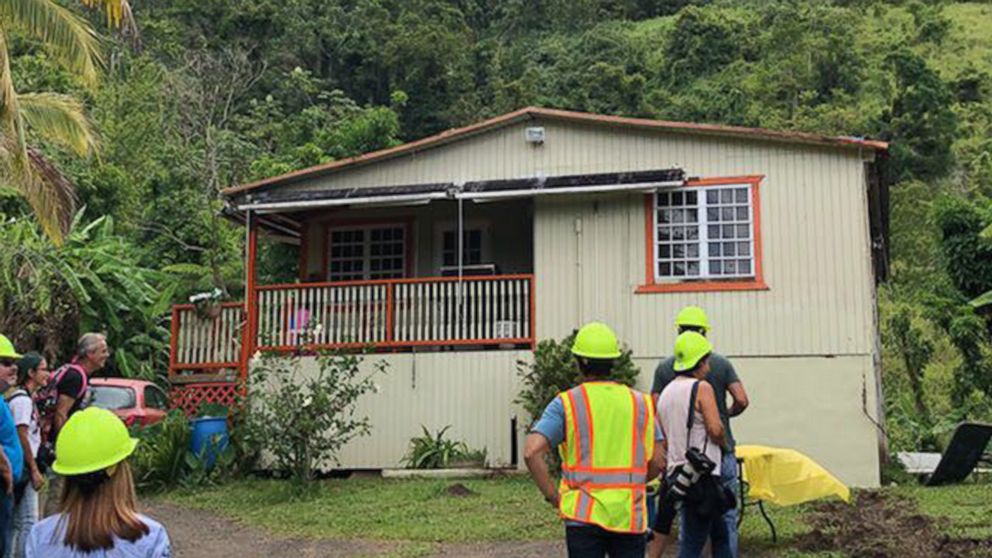 PHOTO: Workers stand outside one of the two homes that had power restored on Aug. 14, 2018, after a mission by the Puerto Rico Electric Power Authority in Ponce.