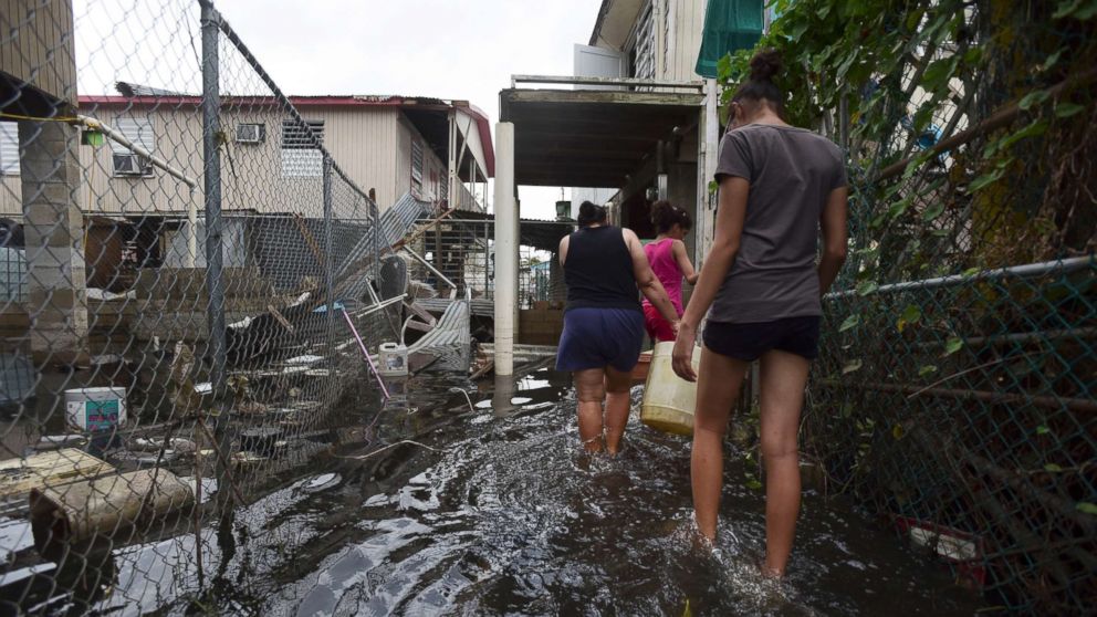 PHOTO: Residents wade through a flooded area in the aftermath of Hurricane Maria, in Catano, Puerto Rico, Sept. 27, 2017. 