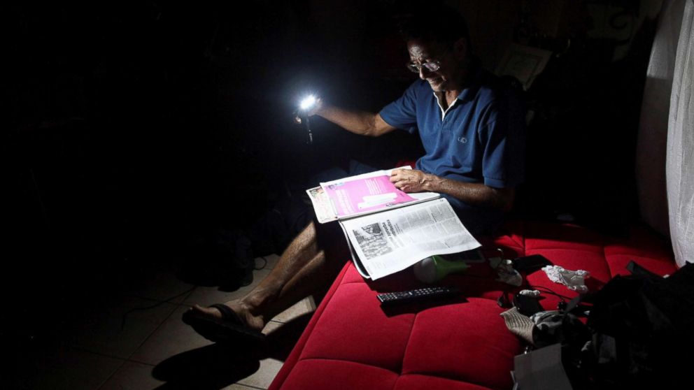 PHOTO: Hugo Regalado reads the newspaper with the help of a flashlight months after Hurricane Maria damaged the electrical grid in Dorado, Puerto Rico, Jan. 15, 2018.