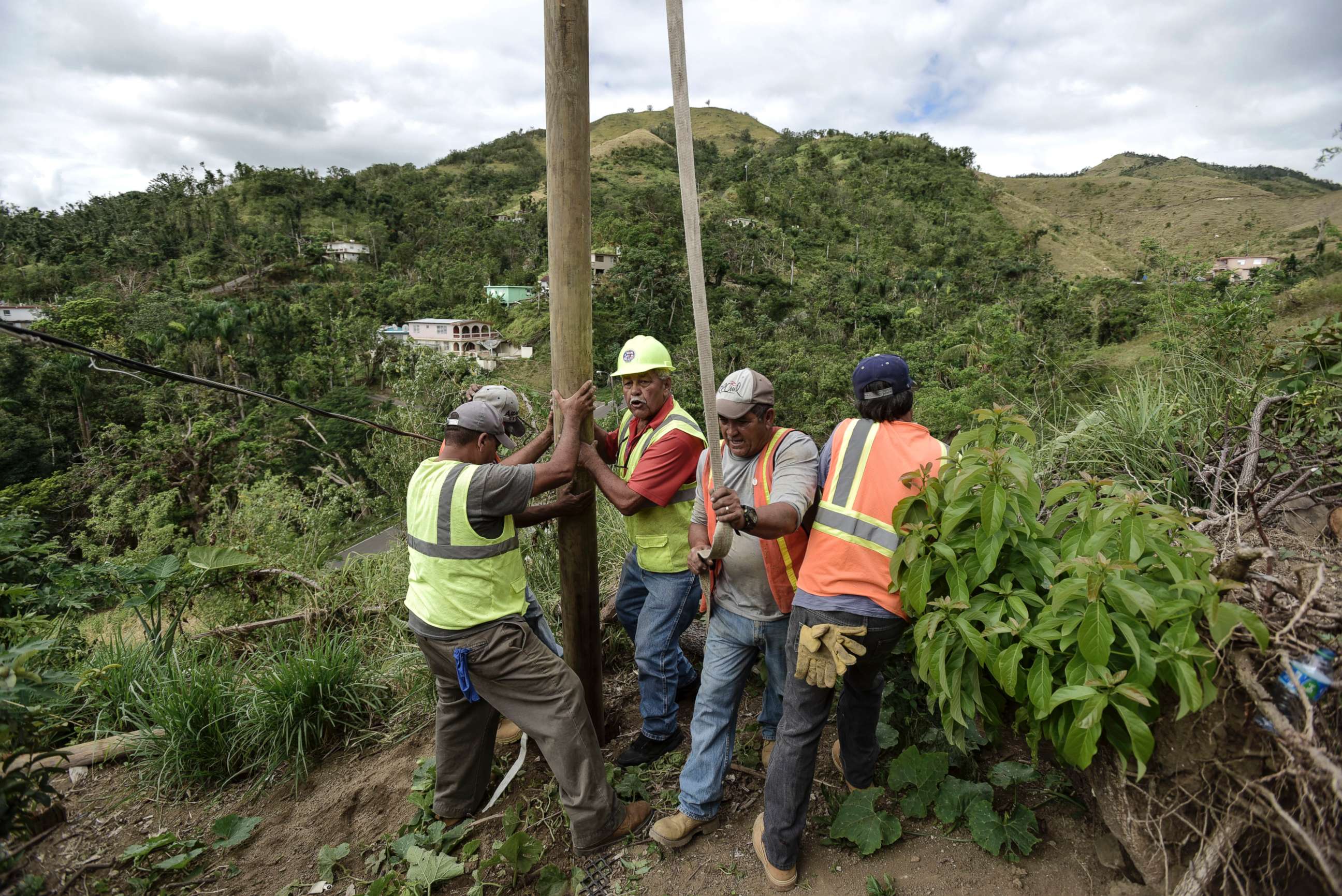 PHOTO: Public Works Sub-Director Ramon Mendez, wearing hard hat, directs locals who are municipal workers, as they install a power pole in an effort to return electricity to a home, in Coamo, Puerto Rico, Jan. 31, 2018.