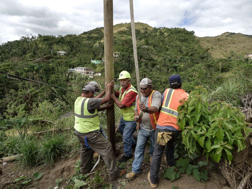 PHOTO: Public Works Sub-Director Ramon Mendez, wearing hard hat, directs locals who are municipal workers, as they install a power pole in an effort to return electricity to a home, in Coamo, Puerto Rico, Jan. 31, 2018.