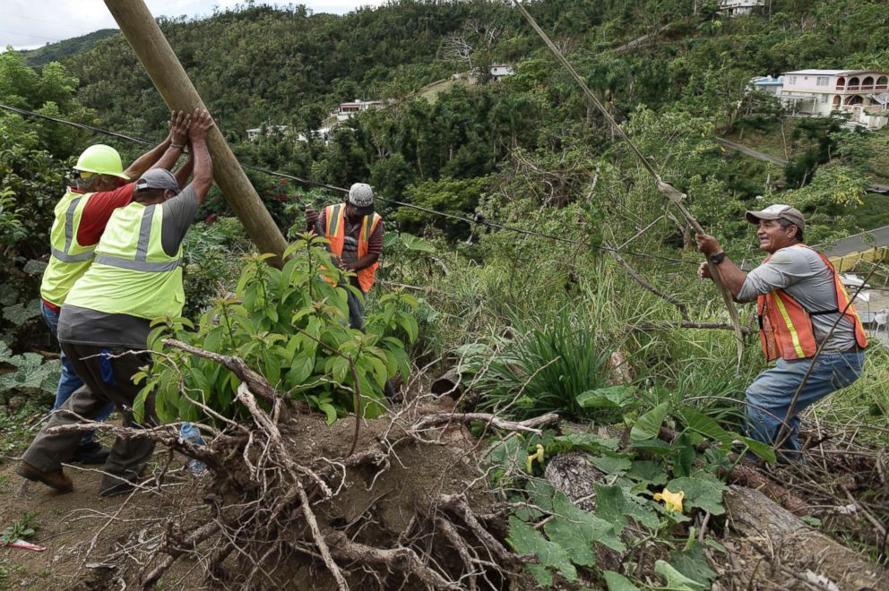 PHOTO: Public Works Sub-Director Ramon Mendez, wearing a hard hat at left, works with locals who are municipal workers, as they install a new post to return electricity to a home in the El Ortiz sector of Coamo, Puerto Rico, Jan. 31, 2018.