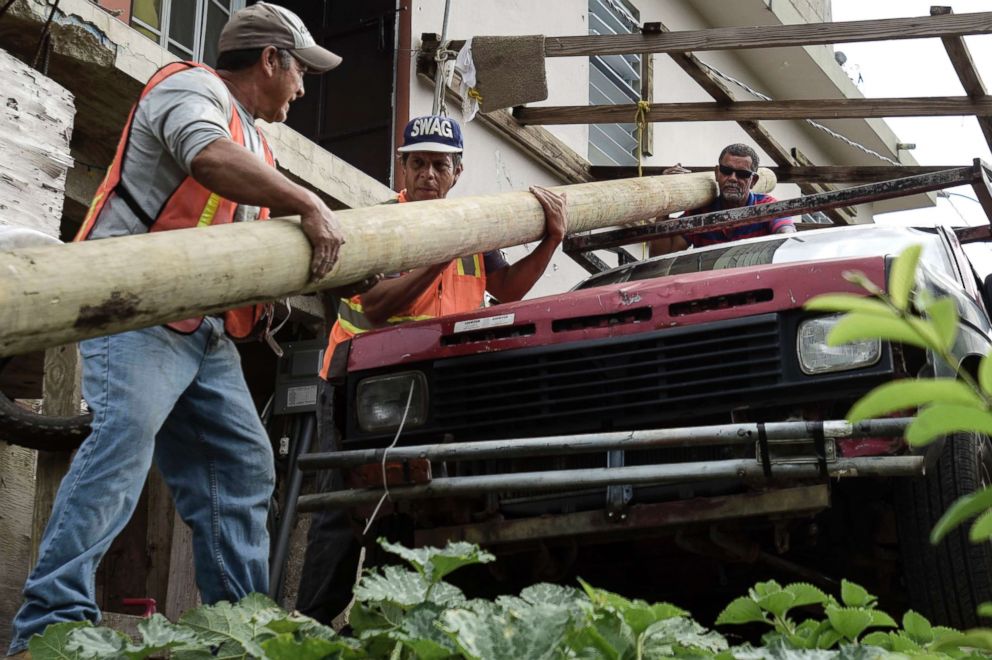 PHOTO: Retired carpenter Felipe Rodriguez, far right, uses his pickup truck to help municipal workers, who are also locals, move an electric post so they can install it near a home, in the El Ortiz sector of Coamo, Puerto Rico, Jan. 31, 2018.