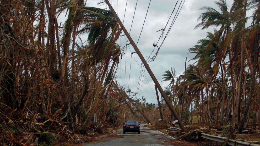 PHOTO: A car drives under tilted power line poles in the aftermath of Hurricane Maria in Humacao, Puerto Rico, Oct. 2, 2017. 