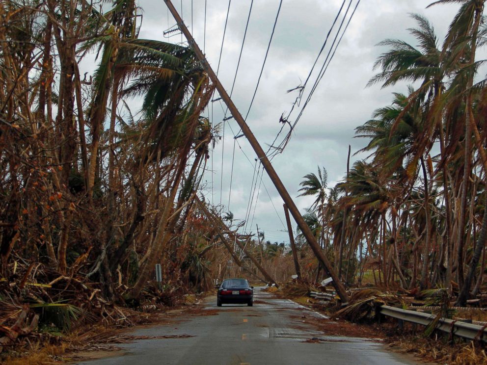 PHOTO: A car drives under tilted power line poles in the aftermath of Hurricane Maria in Humacao, Puerto Rico, Oct. 2, 2017. 