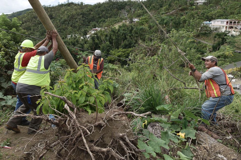 PHOTO: Public Works Sub-Director Ramon Mendez, wearing a hard hat at left, works with locals who are municipal workers to install a new post to return electricity to Felipe Rodriguez's home on Jan. 31, 2018.