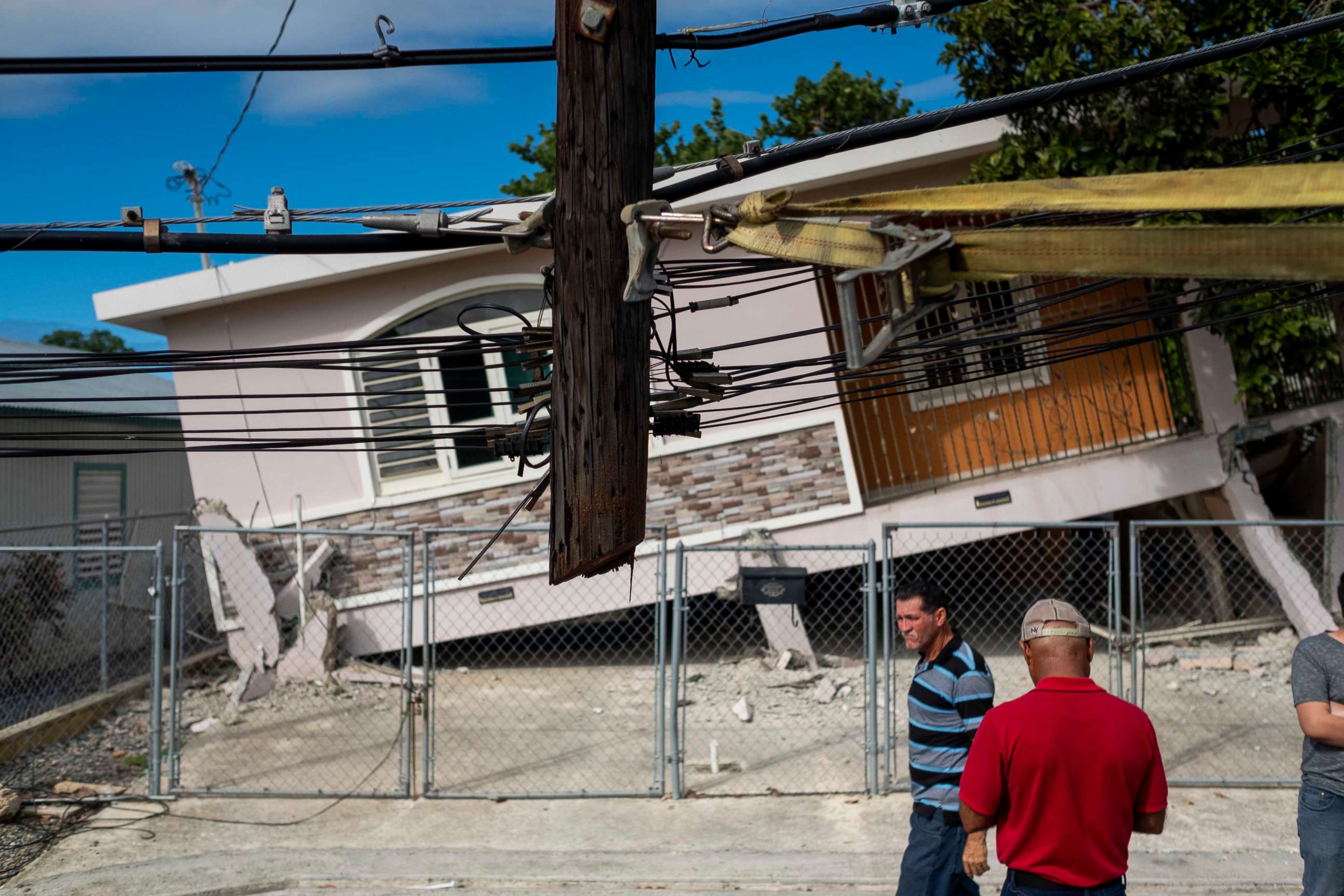 PHOTO: People pass by a house damaged by a 5.8 earthquake in Guanica, Puerto Rico on January 6, 2020. 