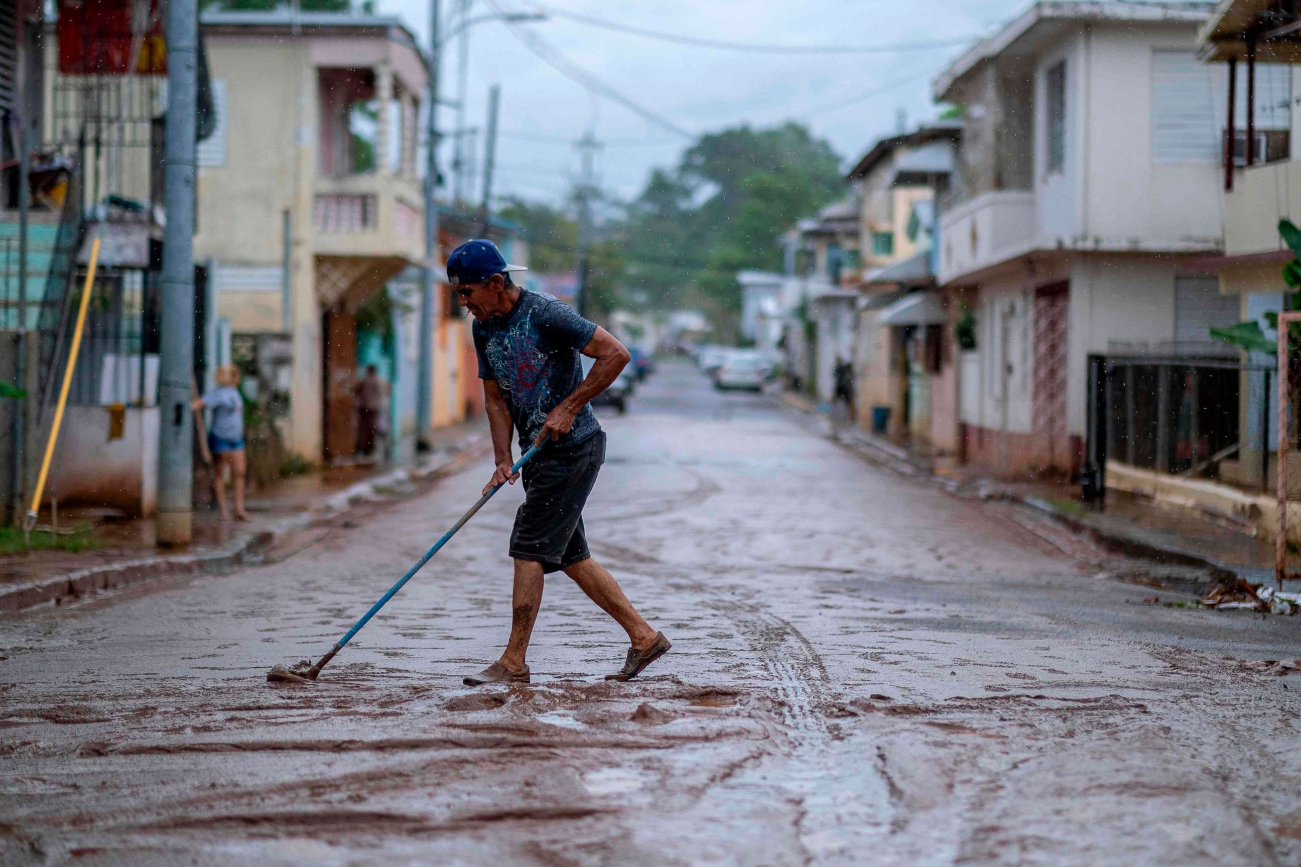 PHOTO: A man sweeps mud from a street after Tropical Storm Isaias swept through the area in Mayaguez, Puerto Rico, July 30, 2020.