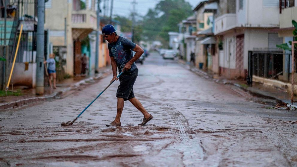 PHOTO: A man sweeps mud from a street after Tropical Storm Isaias swept through the area in Mayaguez, Puerto Rico, July 30, 2020.