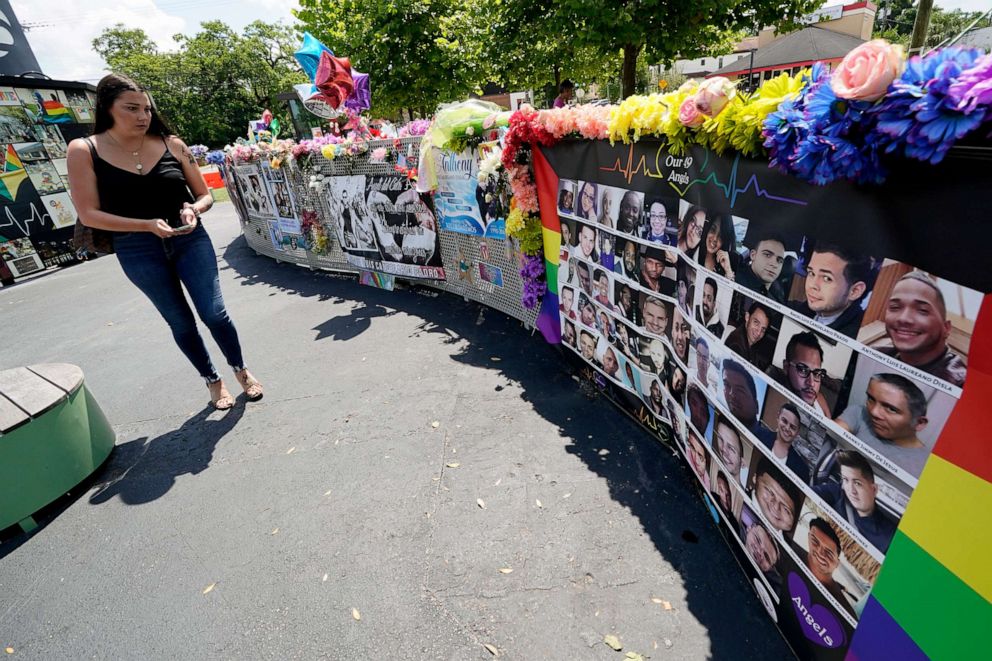PHOTO: In this June 11, 2021, file photo, a visitor looks over a display with the photos and names of the 49 victims that died at the Pulse nightclub memorial in Orlando, Fla.