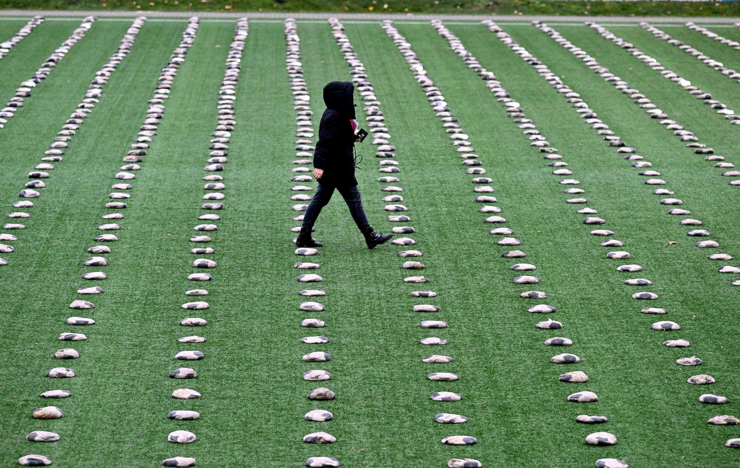 PHOTO: A woman walks between football's like sandbags installed on the pitch of stadium in Herne, western Germany, Nov. 20, 2022, during a protest in remembrance to those who died during the construction of the World Cup stadiums in Qatar.