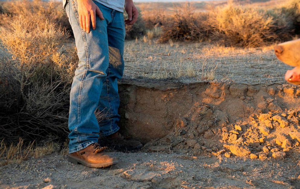 PHOTO: Local resident Steve Latham uses his leg to measure the amount of offset in the desert floor caused by yesterday's magnitude 7.1 earthquake, along California State Route 178 between Ridgecrest and Trona California, July 6, 2019.