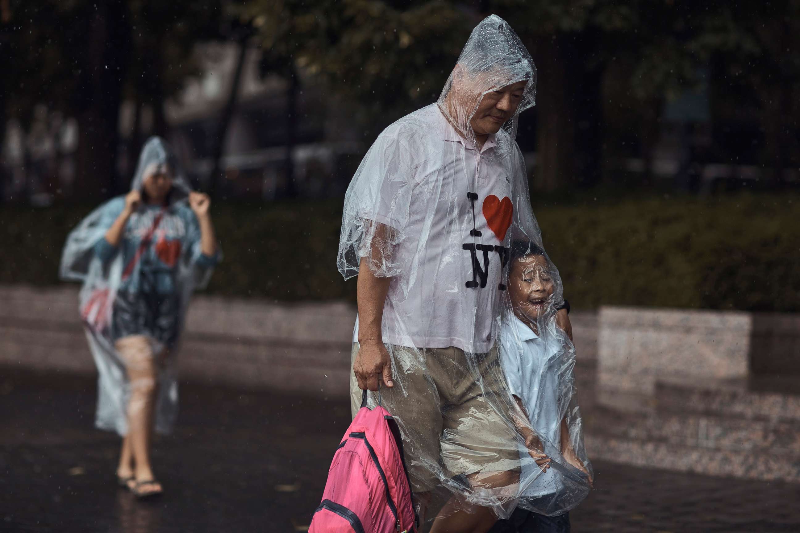 PHOTO: A family walks wearing rain covers, Thursday, July 21, 2022, in New York City.