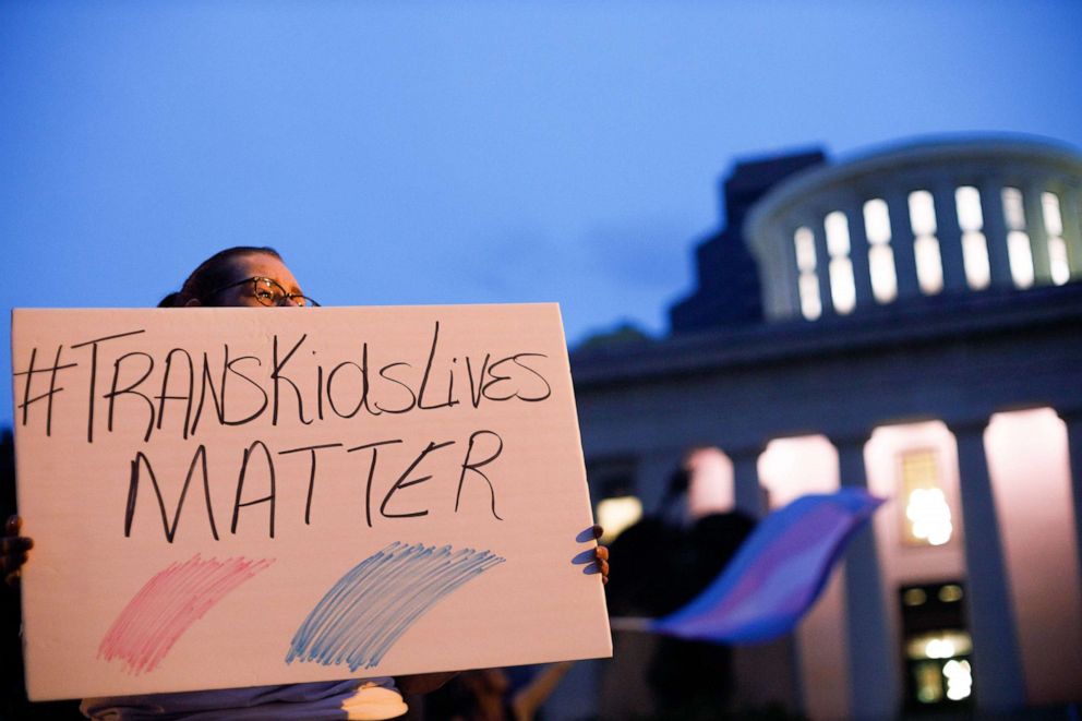 PHOTO: A transgender rights advocate holds a sign outside the Ohio Statehouse during a rally to oppose and bring attention to an amendment to a bill that would ban transgender women from participating in high school and college women sports.