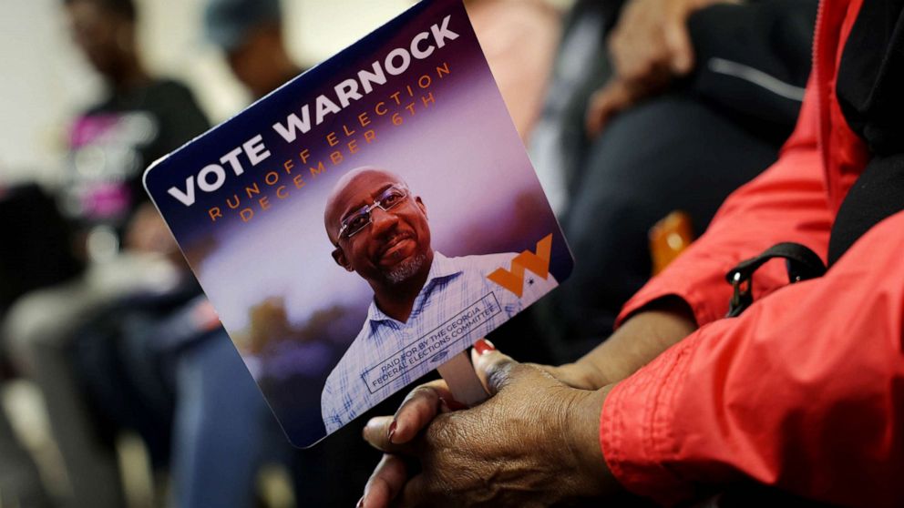 PHOTO: A supporter holds a campaign sign during a campaign rally for Georgia Democratic Senate candidate U.S. Sen. Raphael Warnock, Nov. 30, 2022 in Camilla, Georgia.