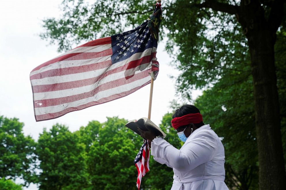 PHOTO: A woman wearing a protective face mask holds a U.S flag outside Ebenezer Baptist Church while funeral is in progress for Rayshard Brooks, the Black man shot by an Atlanta police officer, in Atlanta, June 23, 2020.