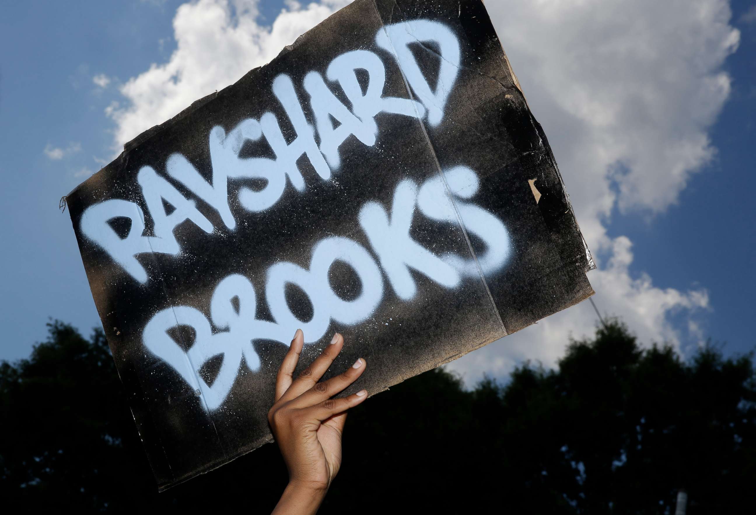 PHOTO: A protester holds up a sign on Saturday, June 13, 2020, near the Wendy's restaurant where Rayshard Brooks was shot and killed by police Friday evening following a struggle in the restaurant's drive-thru line in Atlanta.