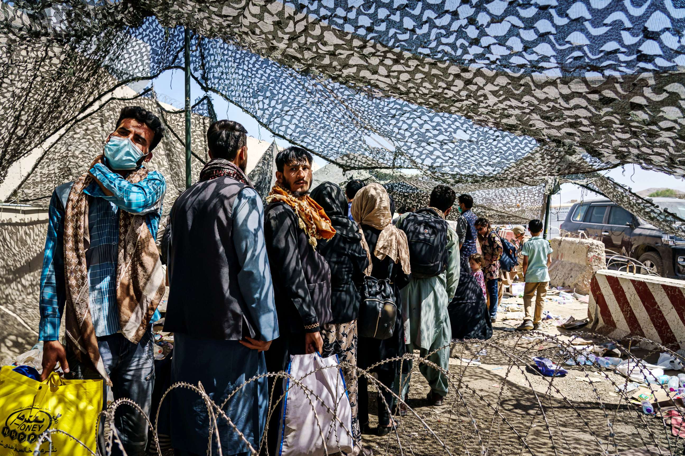 PHOTO: Afghan refugees look back towards the direction they came from as they cross through the processing area to a waiting flight out of Kabul, Afghanistan, Aug. 25, 2021.