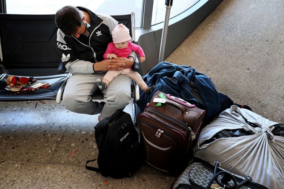 PHOTO: An exhausted refugee holds his baby daughter after arriving at Dulles International Airport after being evacuated from Kabul following the Taliban takeover of Afghanistan, in Dulles, Va., Aug. 27, 2021.