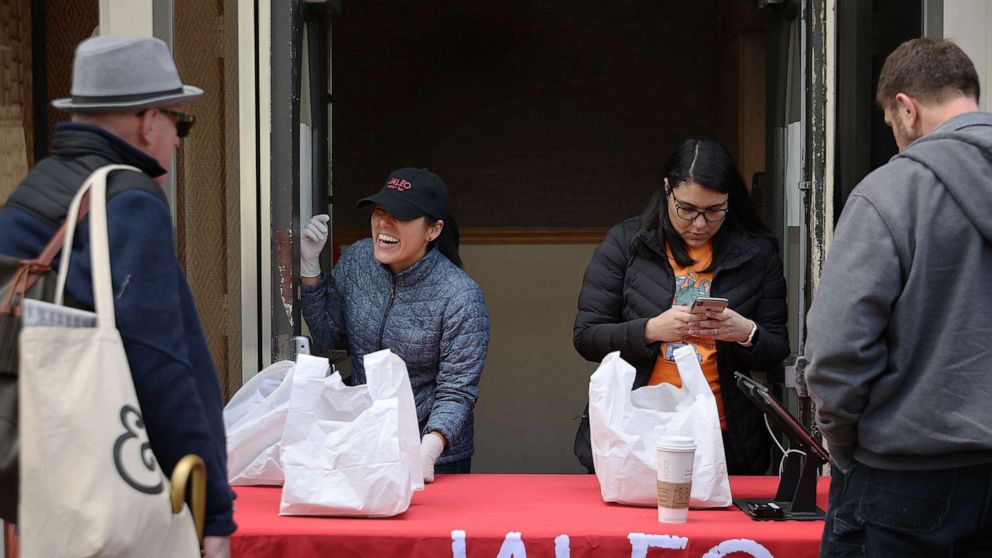 PHOTO: People purchase carry-out lunches out of the back door of Jaleo restaurant in response to the novel coronavirus, March 17, 2020, in Washington, D.C.