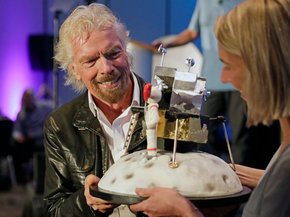 PHOTO: Richard Branson is presented with a space-themed cake during a lunch attended by Virgin Galactic ticket holders, to mark his 69th birthday and in recognition of the Apollo 11 moon landing anniversary Thursday, July 18, 2019, in Cape Canaveral, Fla.