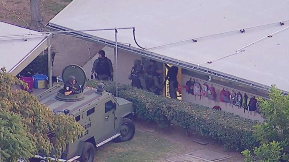 PHOTO: Riverside PD SWAT Team armored vehicle and personnel standing ready before they rescued of 70-year-old Linda Montgomery who was taken hostage by Luvelle Kennon, a parent of her student.