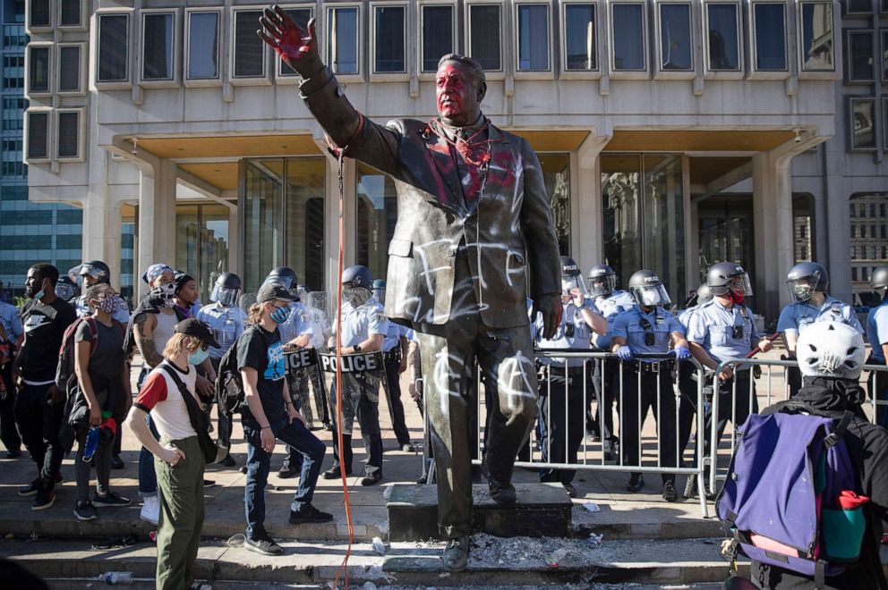 PHOTO: Police and protesters stand near a vandalized statue of controversial former Philadelphia Mayor Frank Rizzo, May 30, 2020 in Philadelphia, during protests over the death of George Floyd.