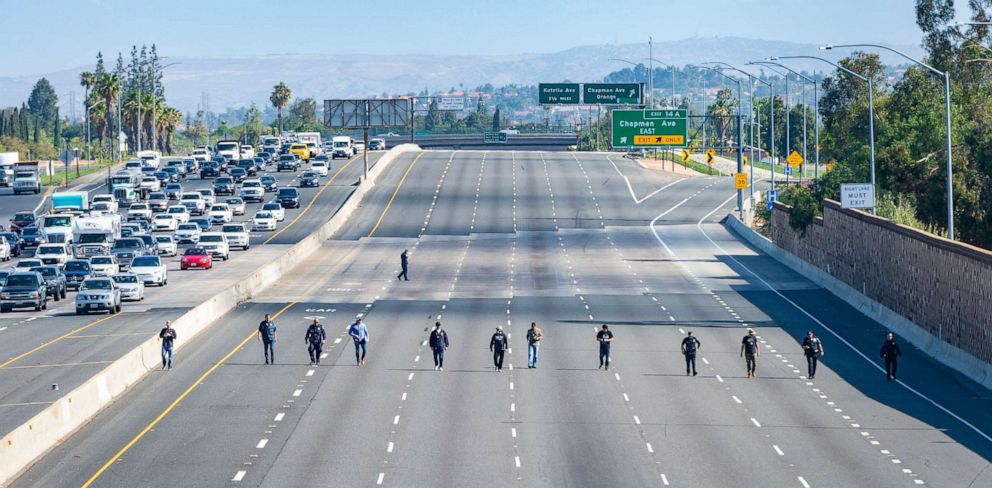 PHOTO: Police investigators walk along the closed northbound lanes of the 55 freeway south of Chapman Avenue looking for evidence following a shooting, Friday, May 21, 2021 in Orange, Calif.