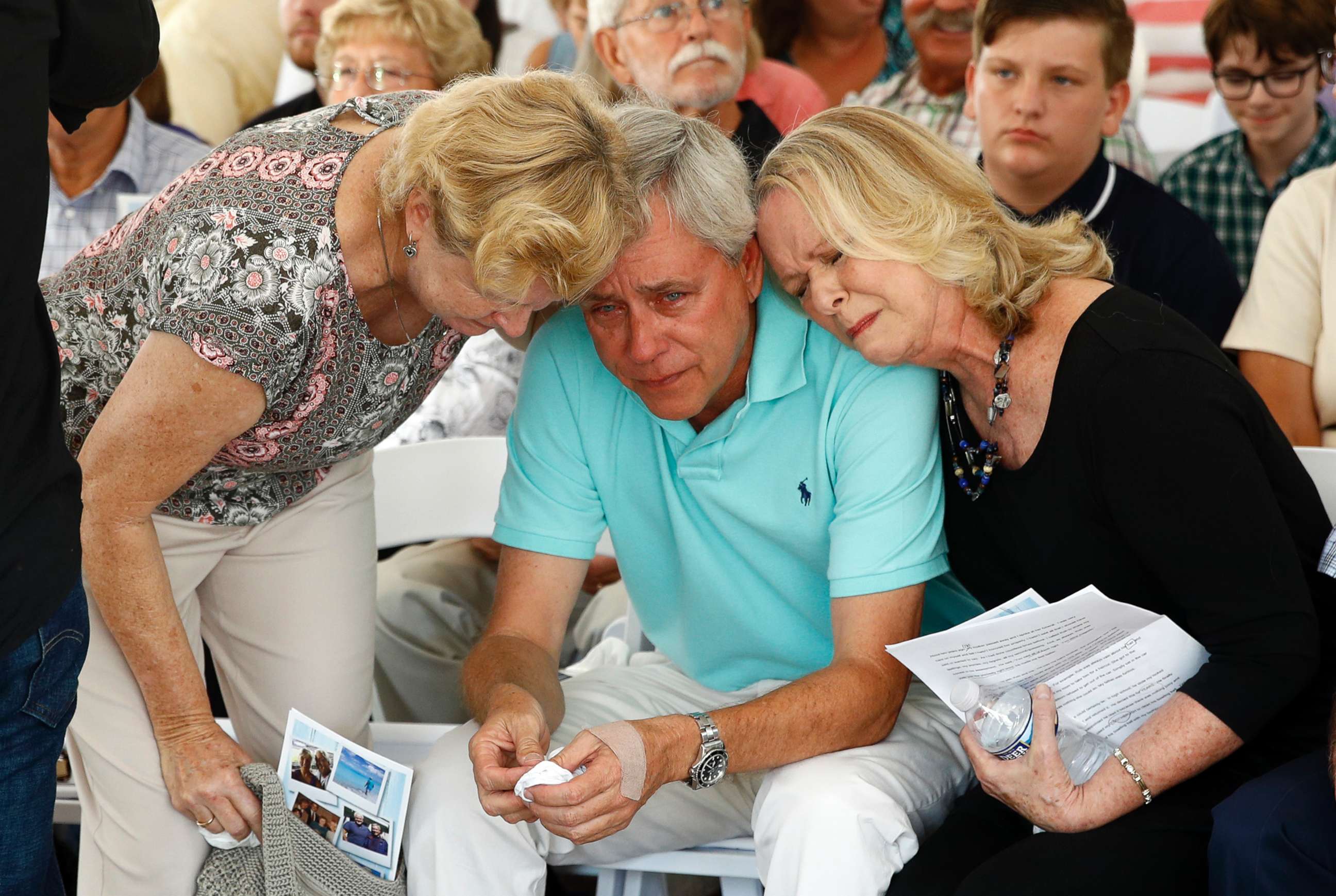 PHOTO: Carl Hiaasen, center, brother of Rob Hiaasen, is consoled by his sister Judy, right, during a memorial service, July 2, 2018, in Owings Mills, Md.