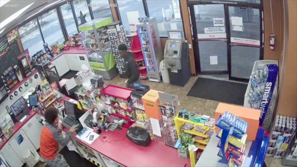 PHOTO: 2 young males appear to step around collapsed clerk to rob store.